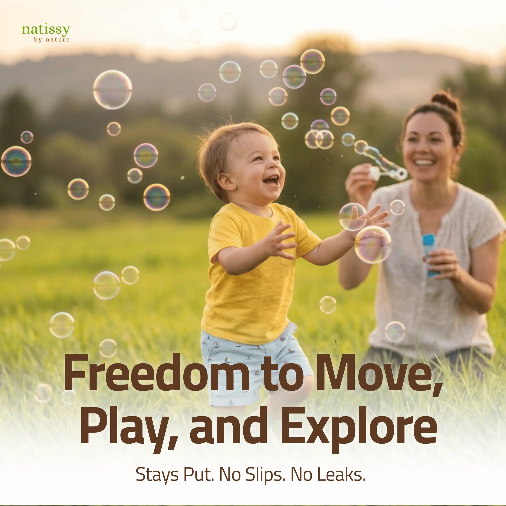 Toddler running through field chasing bubbles with mother, showing freedom of movement with Natissy potty training pads that stay put with no slips or leaks